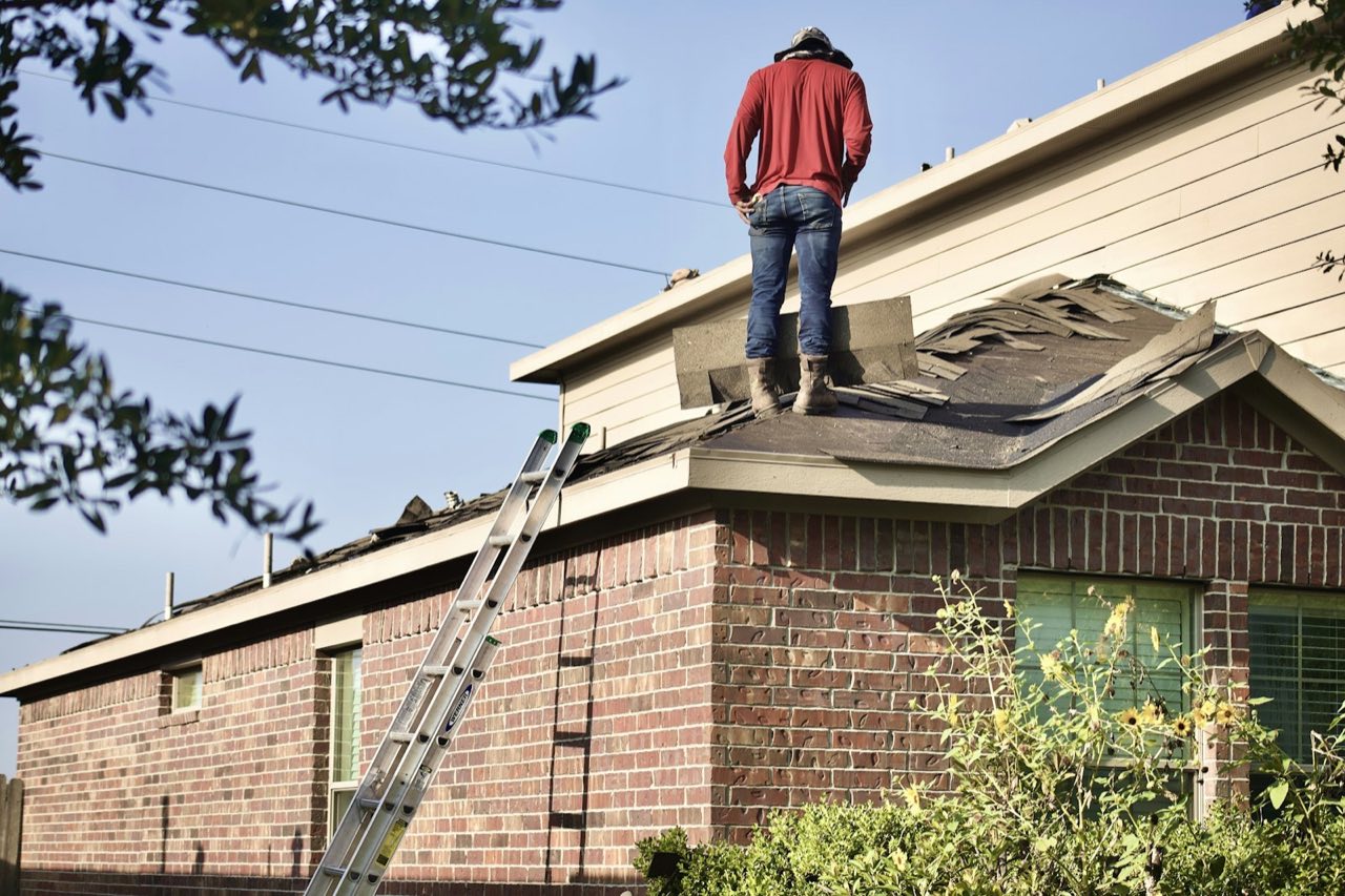 Ridgeline Roofing crew member tearing off old shingles during a roof replacement